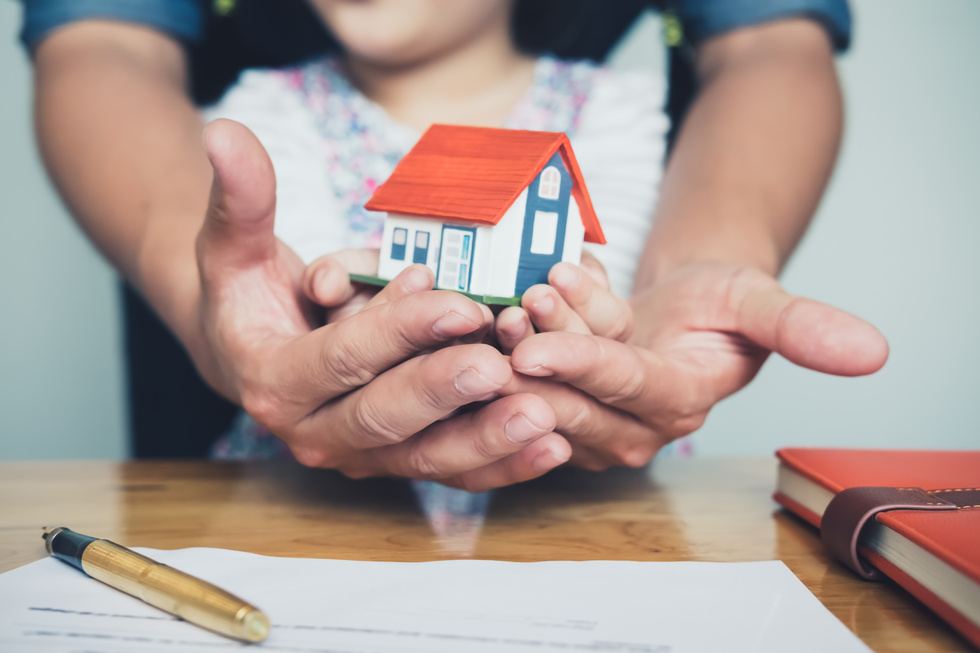 Hands Holding Small House after Signing Contract